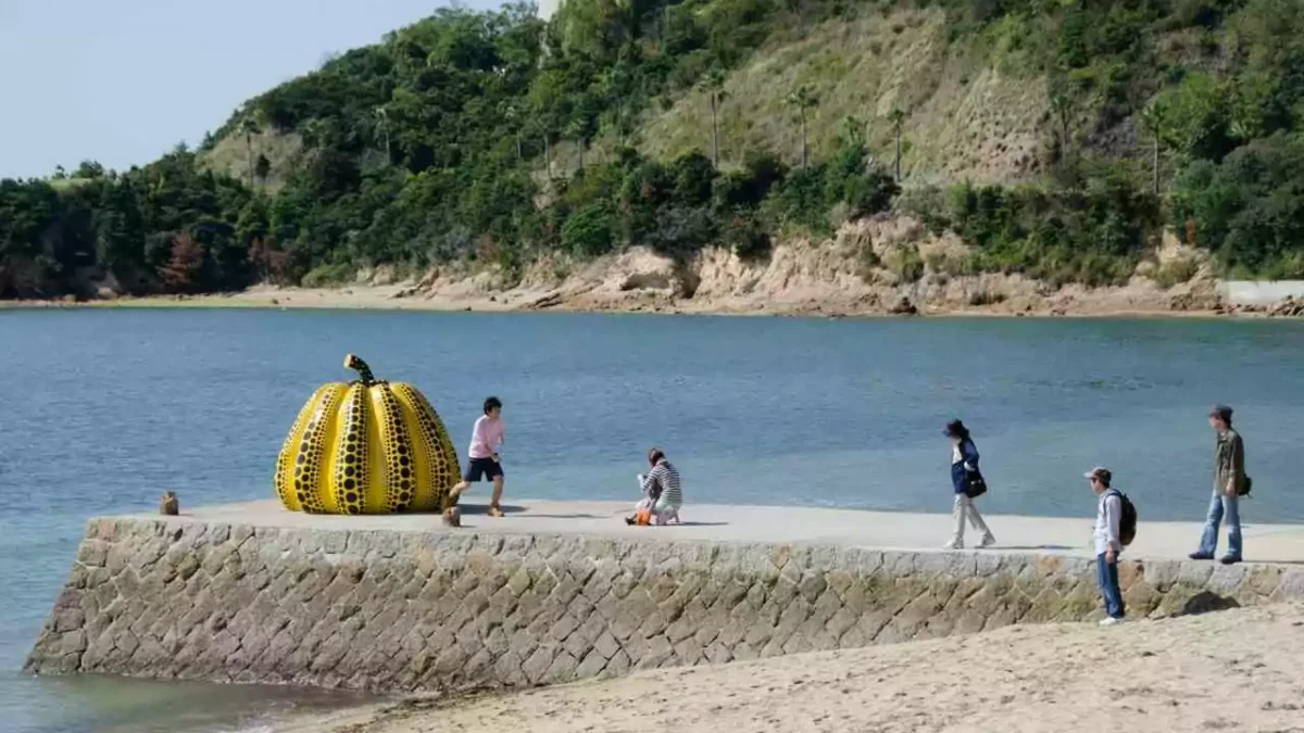 melhores-lugares-para-visitar-no-japao-Naoshima-ilha-de-arte Conheça os melhores lugares para visitar no japão - escultura de abóbora gigante com pessoas fotografando e brincando ao redor, em ilha de Naoshima